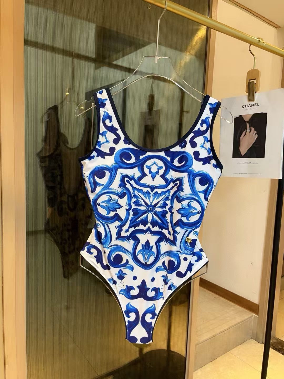Blue and white patterned swimsuit hanging on a hanger with a Chanel magazine in the background.